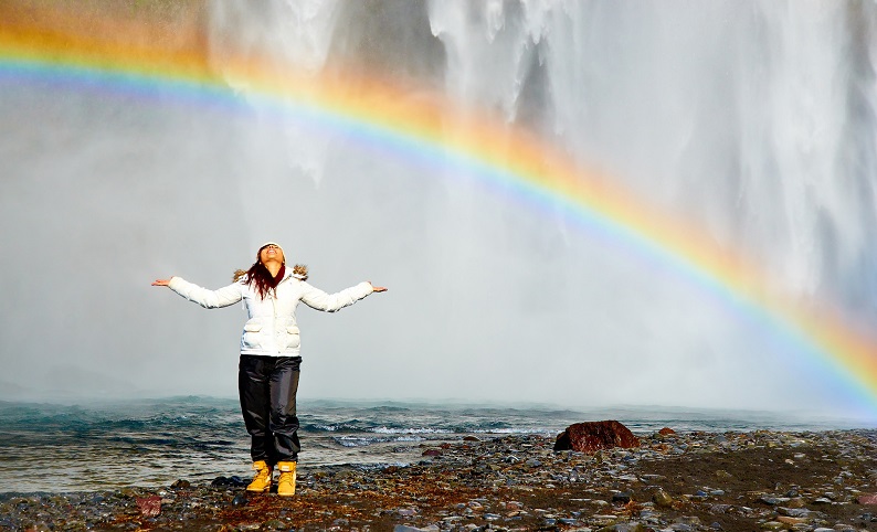 happy woman standing under rainbow
