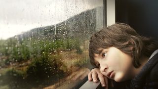upset child looking out train window